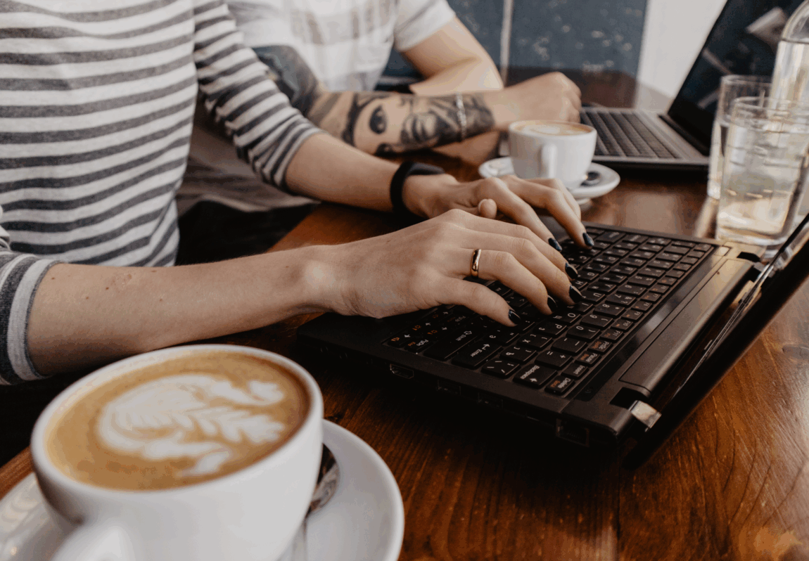 Two professionals collaborating over coffee and a laptop