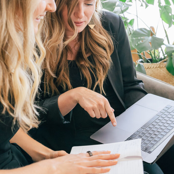 Two Mina Company team members reviewing notes and a laptop